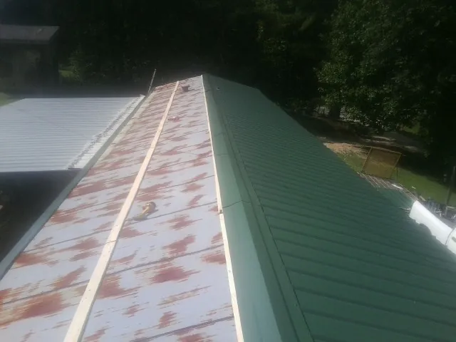 Old rusted panels beside newly installed green metal roofing — Wind Damage Roof Repair by Roofing Brothers in Watchung