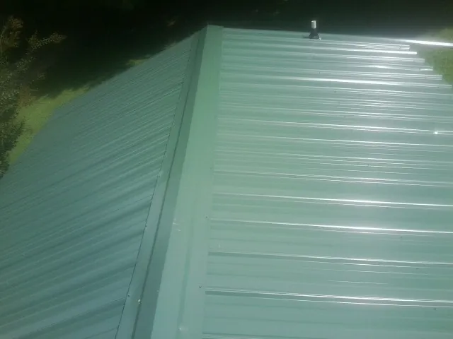 New green metal panels meeting at the ridge of a roof — Flat Roof Repair work by our crew in Watchung