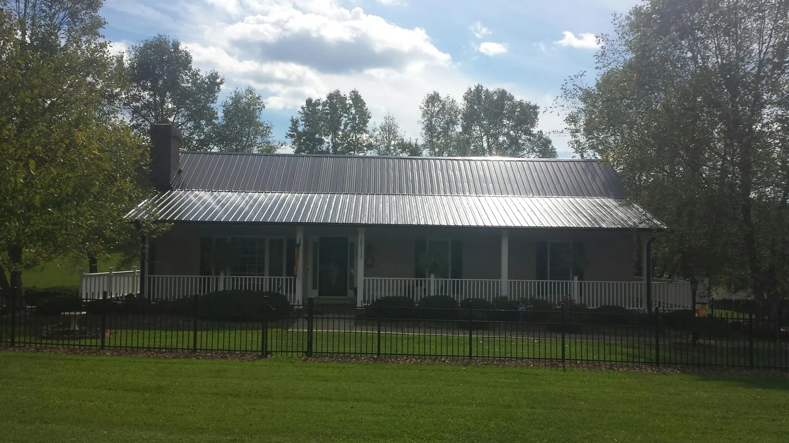 Gray metal roof on a brick ranch with a full width front porch — Gutter Guard Installation work by our crew in Watchung