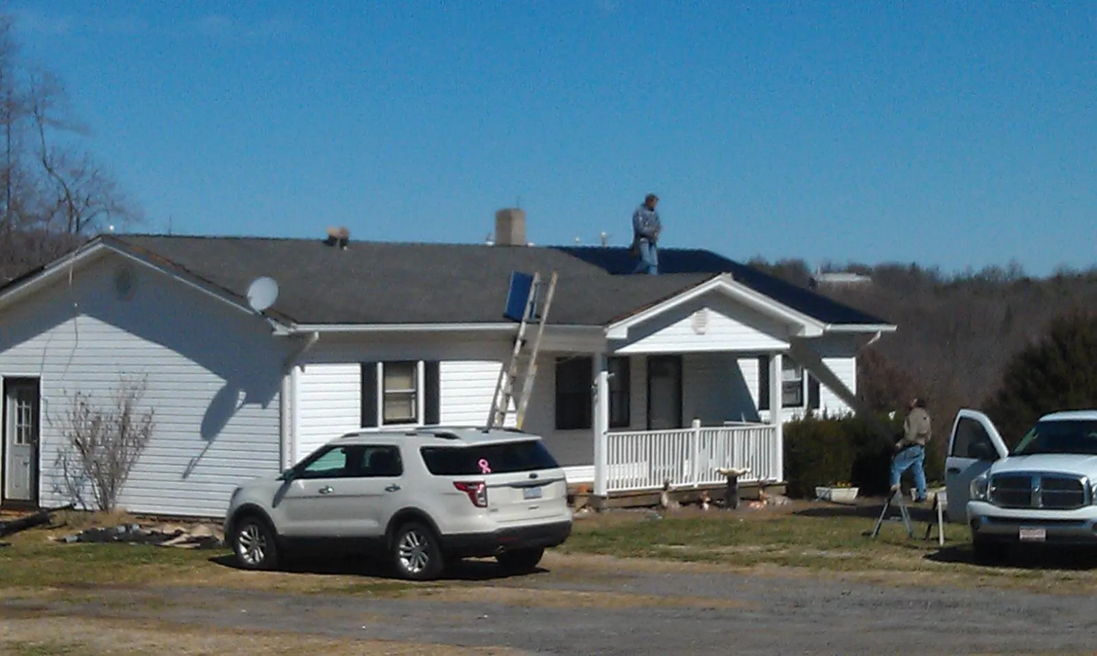 Roofers stripping shingles from a white ranch house roof in Watchung
