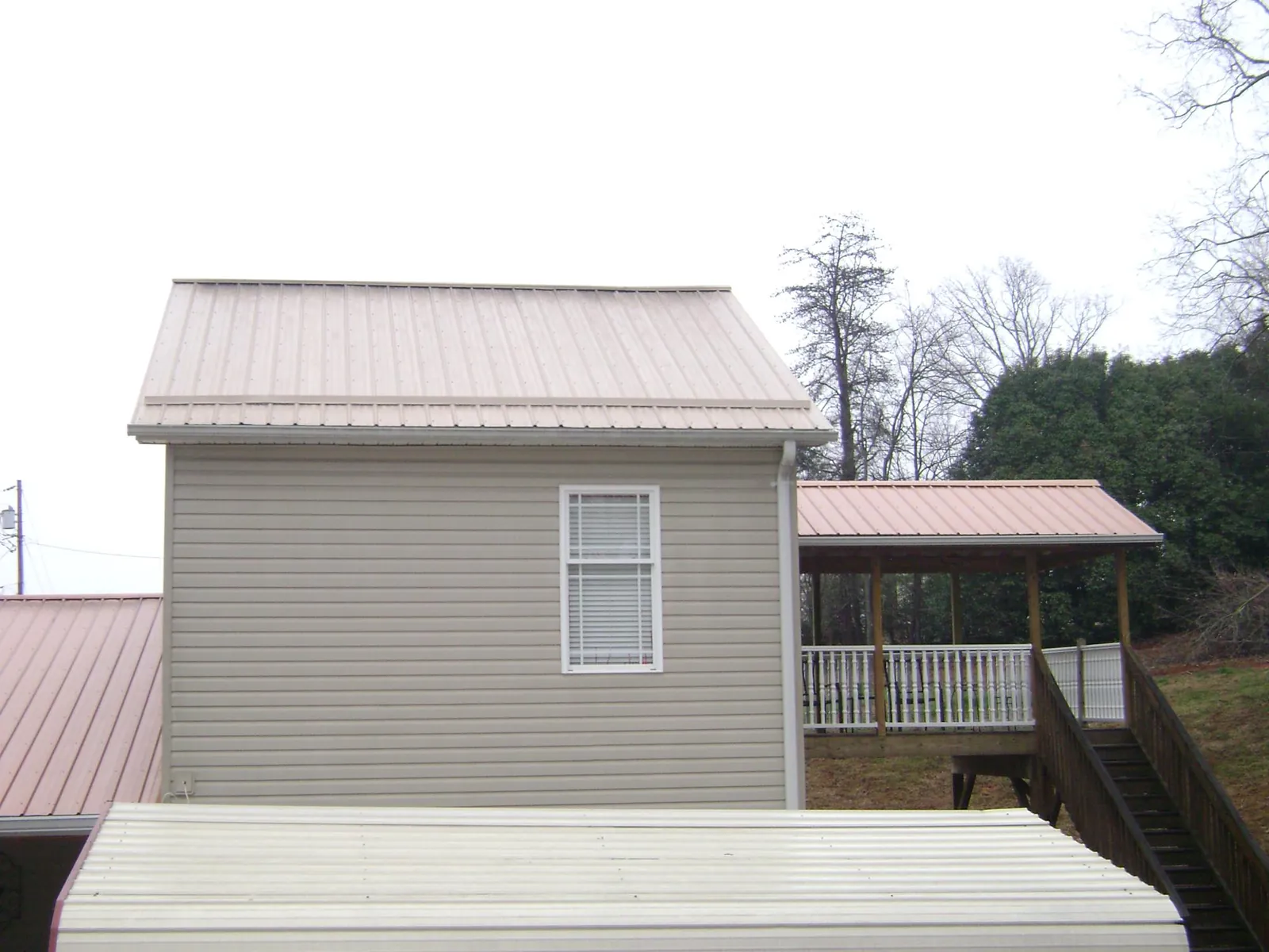 Tan metal roofs on a two story addition and attached porch, from a Roof Replacement job in Watchung