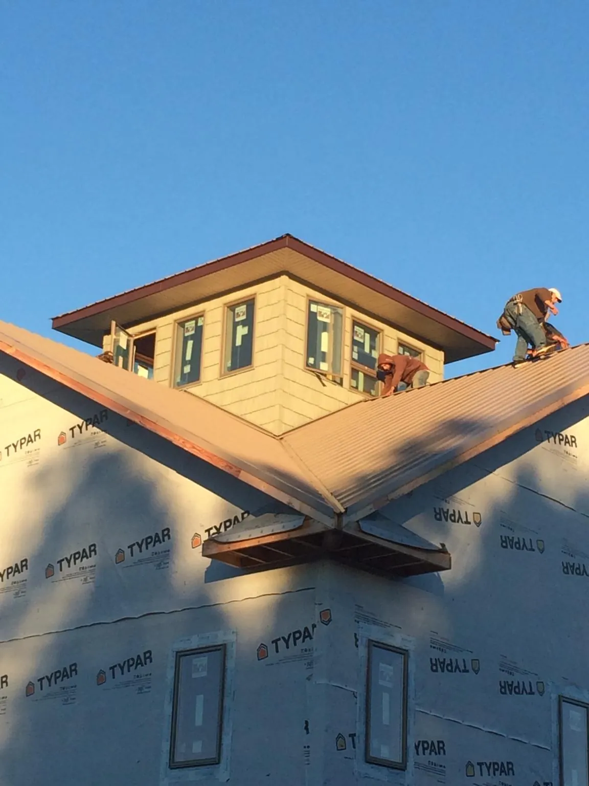 Roofers working around a rooftop cupola on a new metal roof at sunset — Roof Waterproofing in Watchung by Roofing Brothers